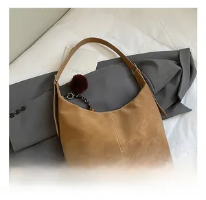 Detail shot of the brown faux suede hobo bag with a red-brown faux fur pompom charm
