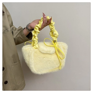 Detail of plush faux fur handbag featuring wrinkled top handle and yellow heart charm