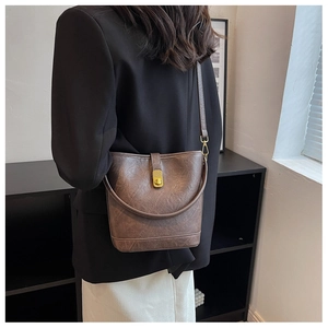Detail shot of vintage brown leather bucket bag with gold lock and textured finish