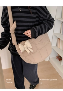 Détail du sac bandoulière matelassé kaki avec nœuds décoratifs porté par un mannequin en studio