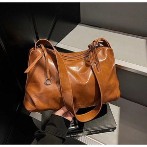 Detail of caramel glossy leather tote bag showing smooth texture and logo debossing