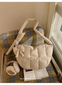 Sac à épaule crème matelassé avec détail de nœud et coutures carrées sur chaise