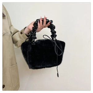 Detail of black faux fur handbag featuring soft texture and pleated leather handle
