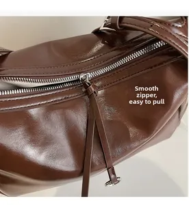 Detail of smooth silver zipper and stitching on brown vintage soft leather tote bag