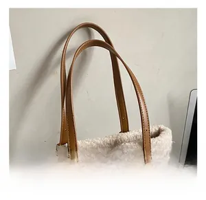 Detail of suede tote bag with white faux shearling trim and adjustable leather handle