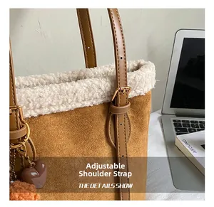 Detail of adjustable leather strap and white faux shearling trim on brown suede bucket bag