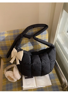 Gros plan d'un sac matelassé noir avec un nœud beige sur une chaise à carreaux