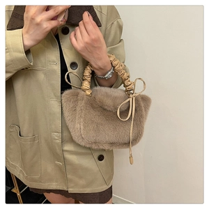 Detail of light brown faux fur handbag with scrunchie handle and decorative bow tie