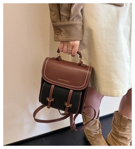 Detail eines Vintage-Lederrucksacks mit Kontrastfarben und goldenen Metallschnallen