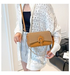Gros plan d'un sac bandoulière marron en cuir texturé avec boucle argentée élégante