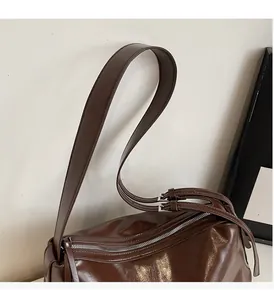 Detail of soft dark brown leather shoulder bag with wide strap and silver metal buckle