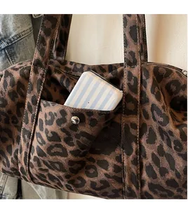 Detail of leopard print canvas bag showing functional front pocket with silver metal button