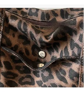 Close-up of leopard canvas bag showing silver magnetic snap and zipper pocket detail