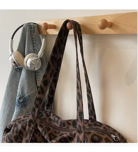 Detail of leopard print canvas tote bag featuring metal zipper and wide shoulder strap