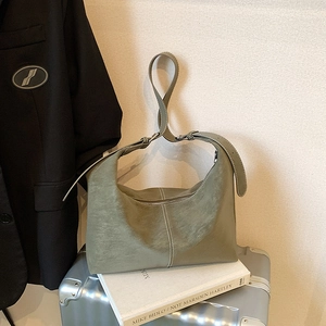 Olive green vintage suede shoulder bag with contrast stitching on white books