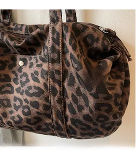 Detail view of leopard print canvas bag showing zipper closure and metal rivet accents