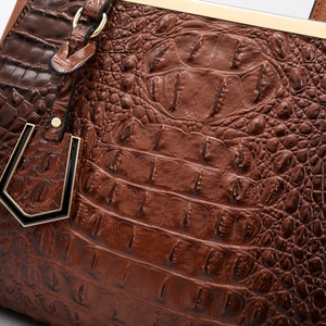 Detailed close-up of dark brown crocodile embossed leather with gold metal accents
