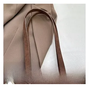 Gros plan sur un sac cabas en daim marron avec poignée confortable et détails rivets