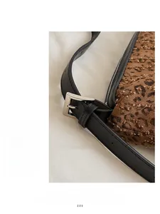 Close-up of leopard print fabric with black leather strap and silver adjustable buckle