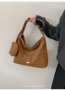 Detail of caramel hobo bag with contrast stitching and detachable mini pouch accessory