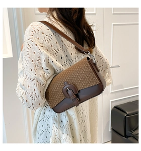 Modèle portant un sac bandoulière patchwork en cuir et paille avec boucle fer à cheval