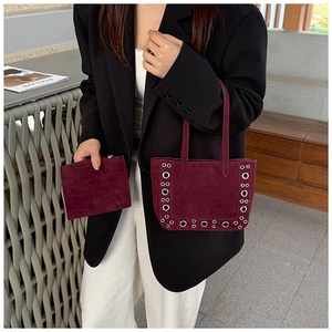 Détail du sac cabas en daim bordeaux avec œillets argentés et pochette assortie