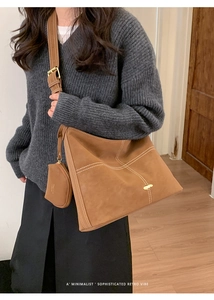 Detail of retro brown suede tote with white contrast stitching and a gold oval buckle