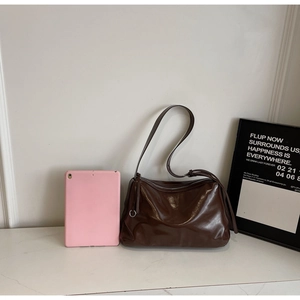 Brown soft oil wax leather tote bag with tablet for size reference on marble surface