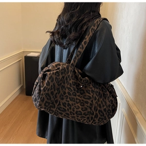 Detailed shoulder view of large leopard print canvas tote bag on a model in black coat