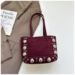 Détail d'un sac cabas en daim bordeaux avec clous et œillets métalliques argentés