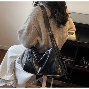 Black soft PU leather tote bag with pleated detail shown in a stylish shoulder carrying view