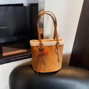 Brown suede bucket bag with white faux shearling trim and decorative plush pendant
