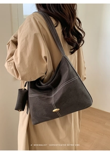 Detail of charcoal grey suede tote with contrast stitching and cylindrical pouch