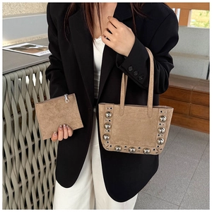 Gros plan du sac fourre-tout en daim marron avec rivets et petite pochette zippée assortie