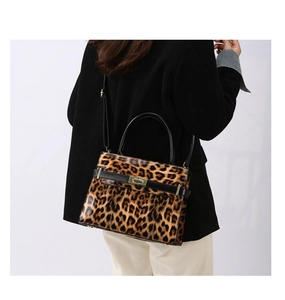 Detail der Handtasche mit Leopardenmuster und goldenem Drehverschluss am schwarzen Mantel