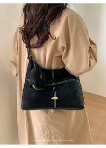 Close-up of black suede tote bag with white stitching and gold hardware detail
