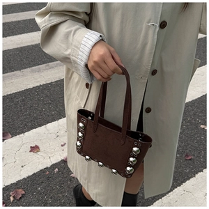 Détail du sac à main en daim marron foncé avec de gros rivets métalliques argentés