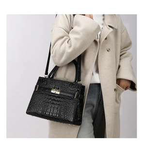 Model mit schwarzer Handtasche in Krokoprägung, goldener Schließe und elegantem Trageriemen