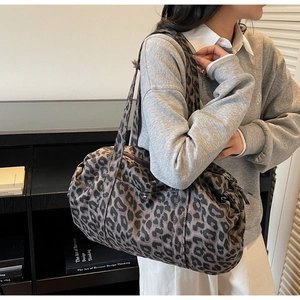 Detailed view of leopard print canvas bag worn as a shoulder bag in high texture
