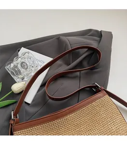 Dettaglio della borsa in paglia intrecciata con tracolla in pelle marrone e fibbia