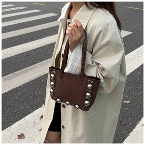 Gros plan d'un sac à main en daim marron avec rivets dans un décor de rue urbain