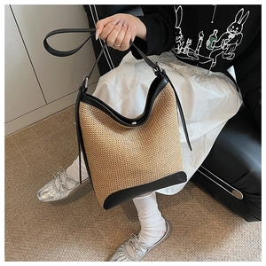 Dettaglio della borsa tote in paglia intrecciata con finiture e manici in pelle nera