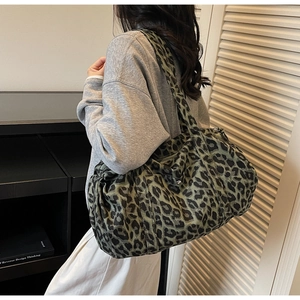 Close-up of a dark green leopard print canvas shoulder bag with wide strap and side pocket