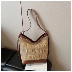 Primo piano dettagliato di una borsa tote intrecciata con finiture in pelle marrone e anelli
