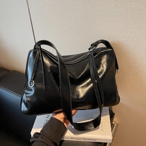 Large black glossy leather tote bag with silver ring detail and minimalist commuter design