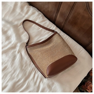 Dettaglio della trama in paglia e dei cinturini in pelle marrone di questa borsa estiva