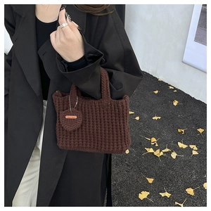Detailed close-up of brown waffle knit handbag with Hand Made tag and autumn leaf decor