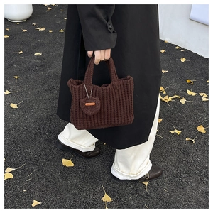 Detail of dark brown knitted handbag with textured weave and heart handmade tag