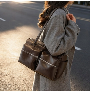 Street style view of a brown vintage tote bag with metal zippers on a grey wool coat