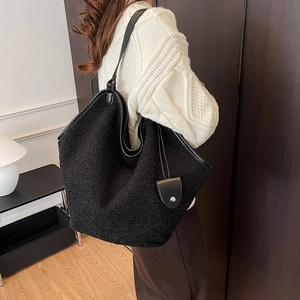 Detail of black faux shearling tote bag with leather straps on model's shoulder